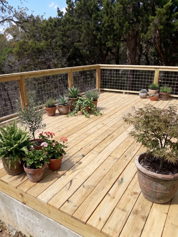 Custom wood deck with hog-wire railing and potted plants built by Cardenas Landscaping