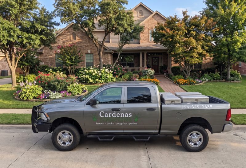 The branded Cardenas Landscaping work truck parked in front of a home with mature landscaped flower beds and a manicured lawn